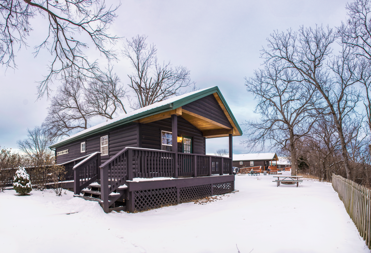 A dark brown wooden cabin surrounded by snow.